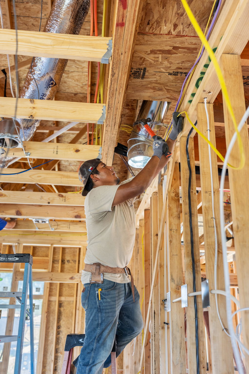 A craftsperson installing services within Oakline's timber frame